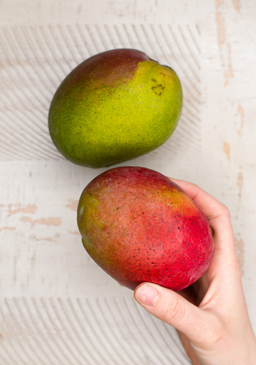 two ripe mangos on tan background