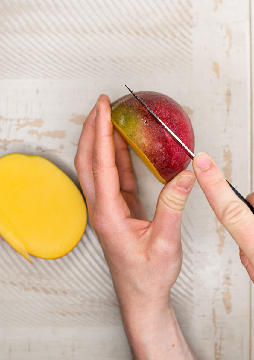 hands cutting mango with a knife