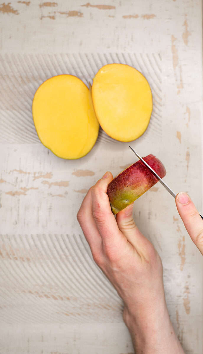 hands cutting remaining two sides of a mango