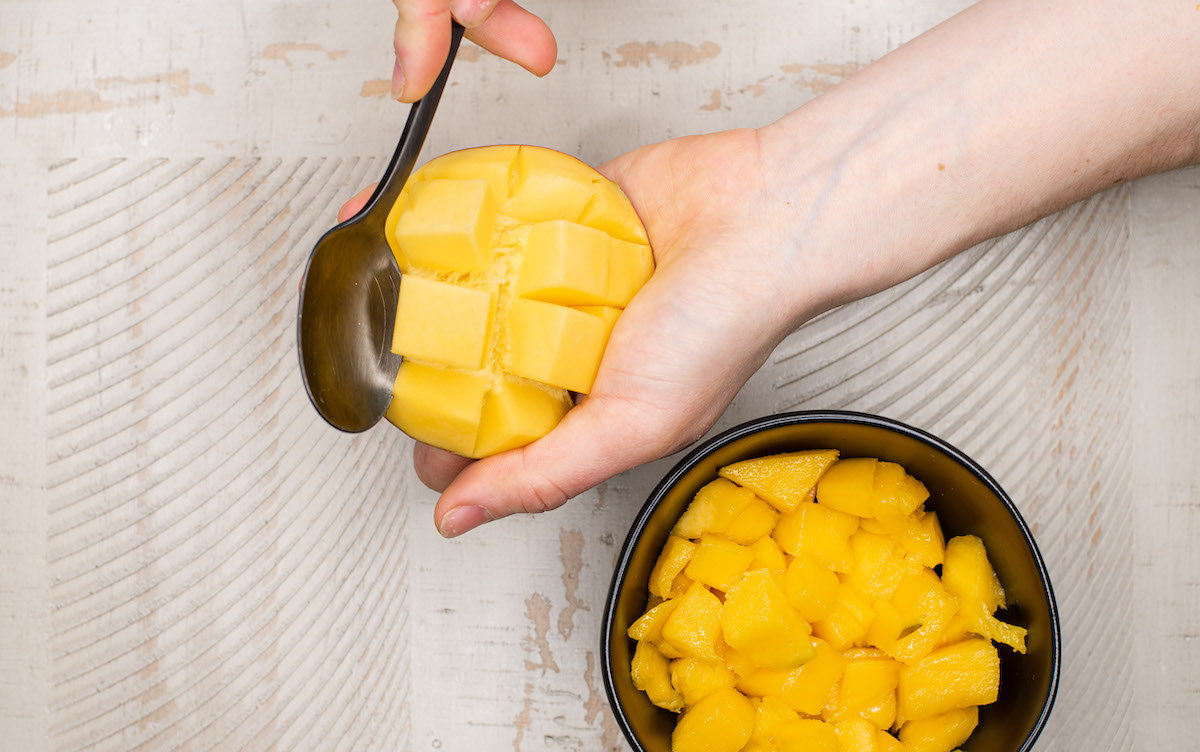 peeling mango with a spoon