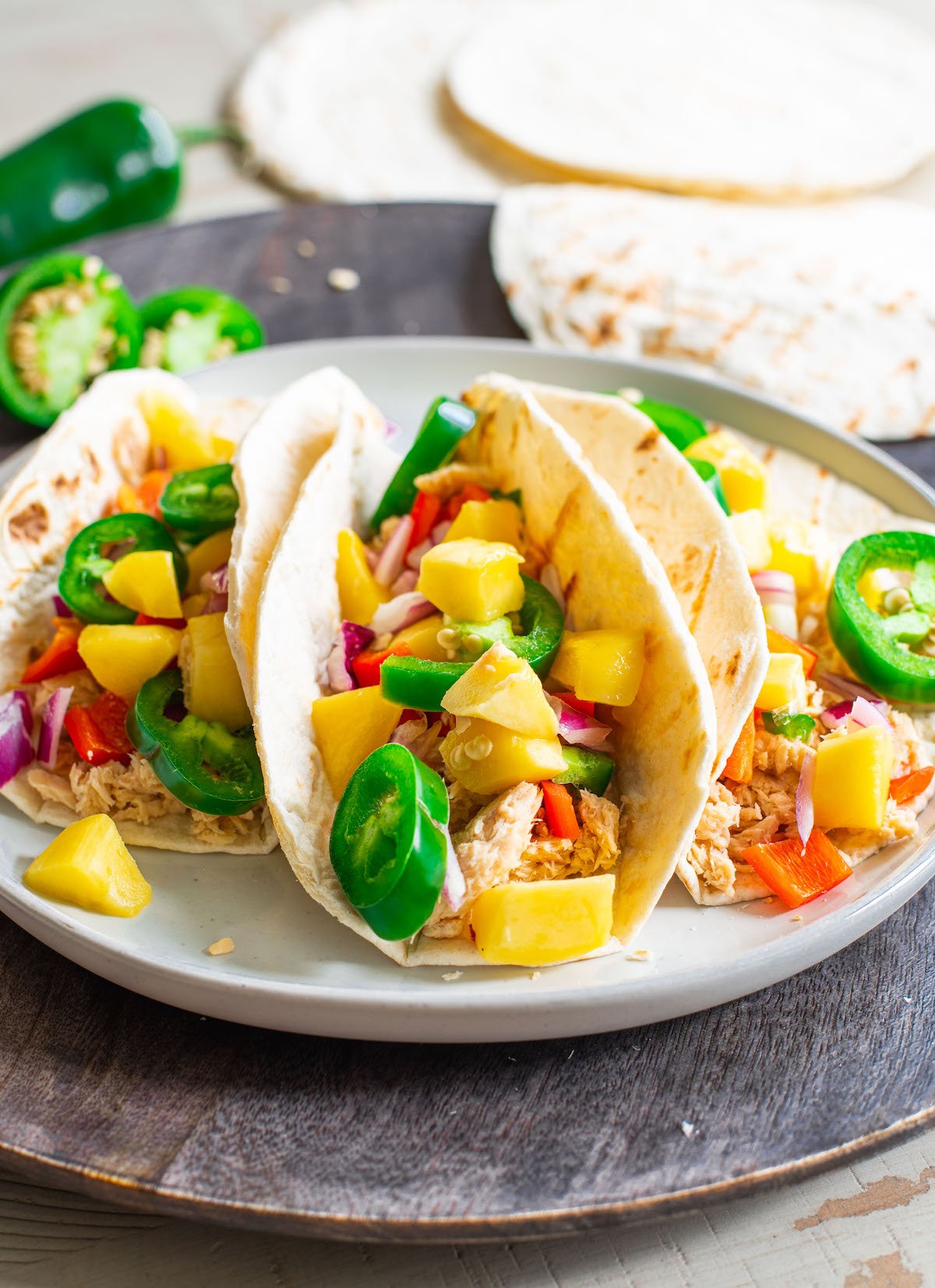canned salmon tacos filled with mango salsa on a dark plate