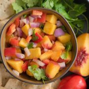 bowl of mango habanero salsa with chips and a sliced peach