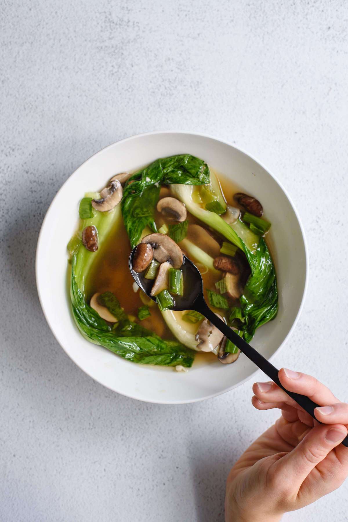 spoonful of soup with mushrooms and scallions