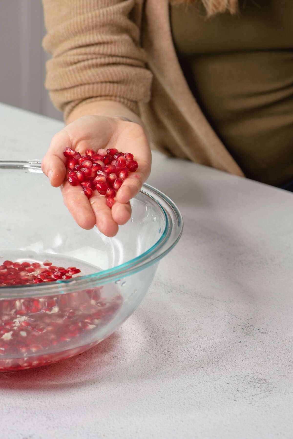 hand holding pomegranate seeds during pomegranate season 