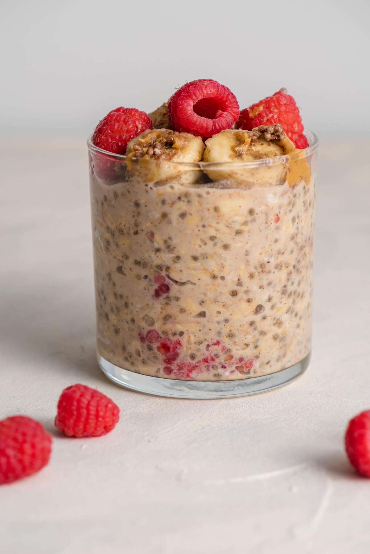glass of raspberry overnight oats with water