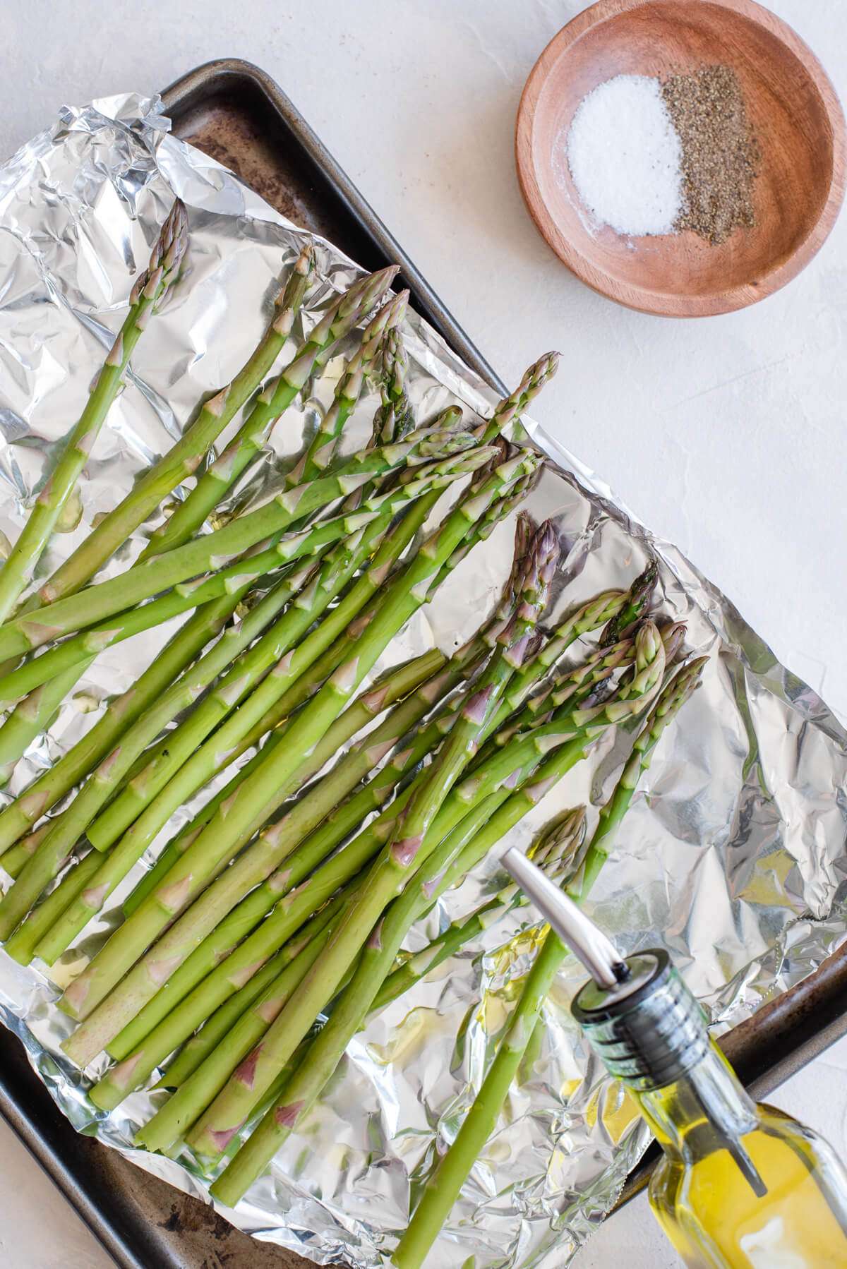 grilled asparagus in foil being seasoned with olive oil