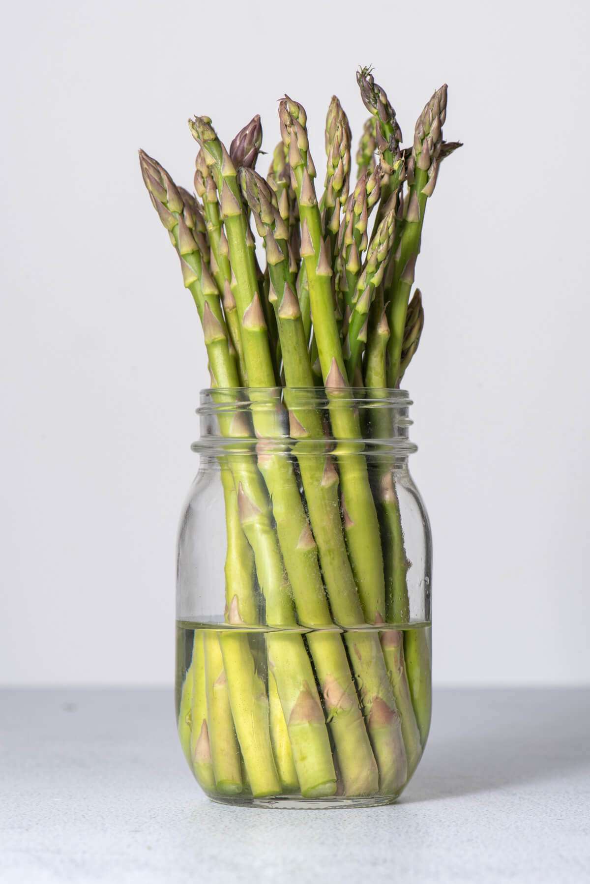 asparagus spears stored in a mason jar with water