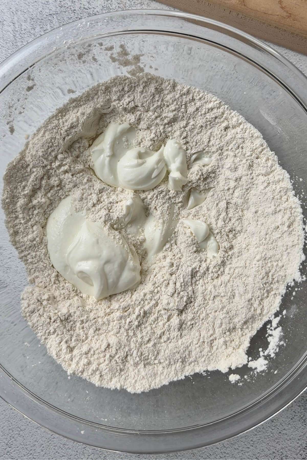 clear mixing bowl with flour, baking powder, salt, and greek yogurt